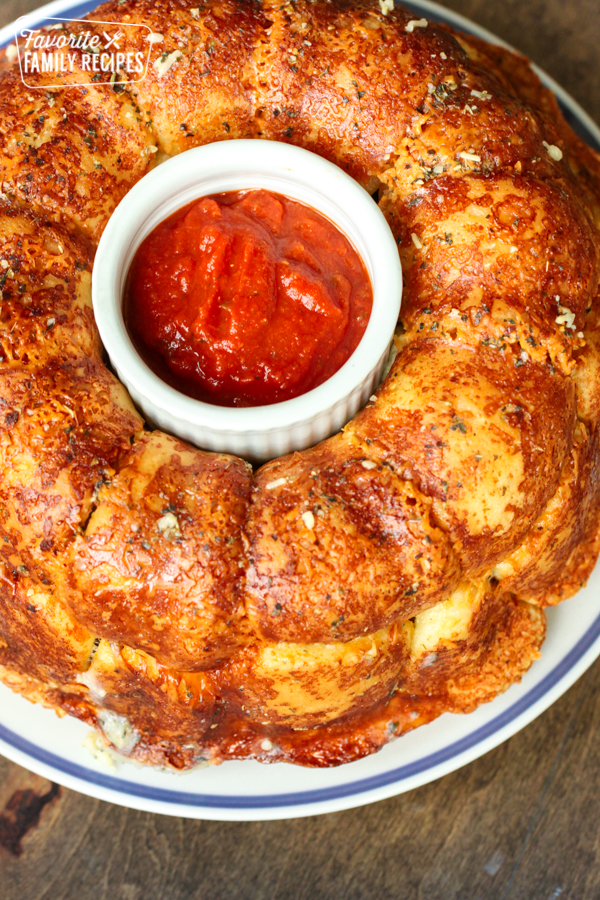 A ring of Parmesan pull apart bread with marinara sauce in a small bowl in the middle