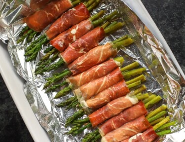 Prosciutto Wrapped Asparagus on a white serving platter