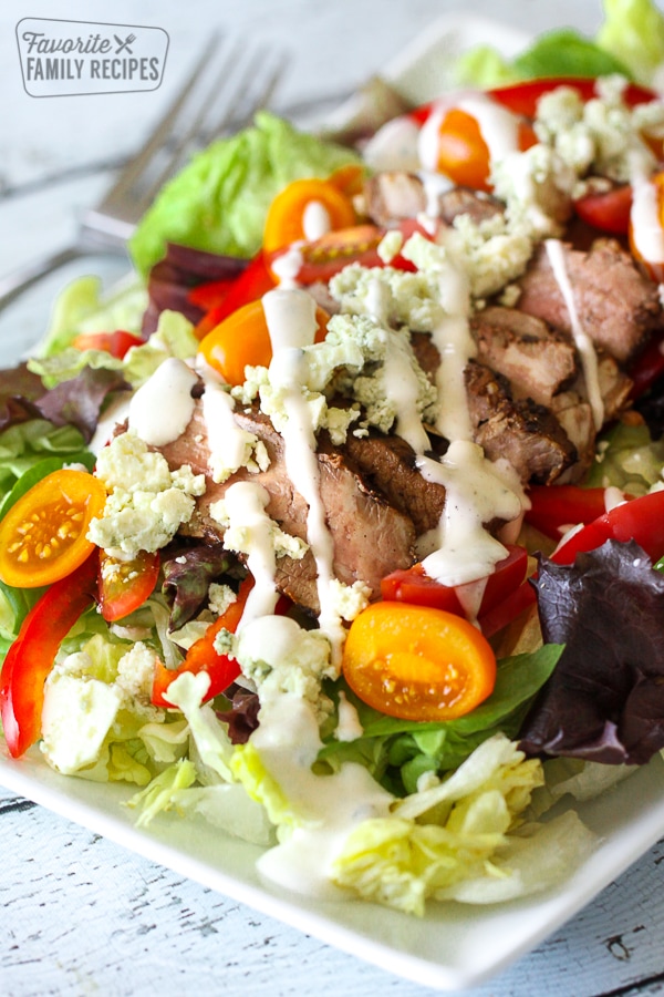 Steak salad with bleu cheese sprinkles and blue cheese dressing drizzled on top