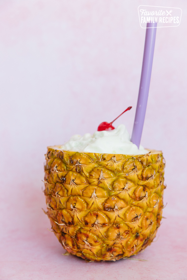 Tropical Slush served in a hollowed out pineapple with a purple straw.