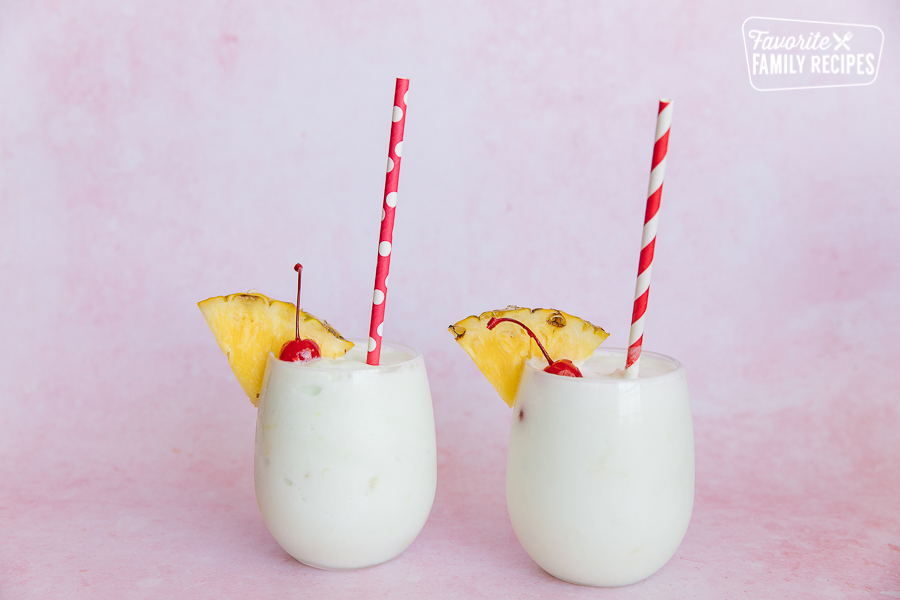 Two tropical slush drinks in clear cups and decorative straws.