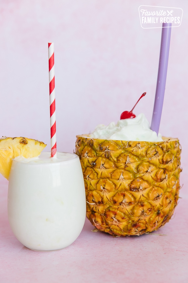 Two tropical slush drinks one served in a clear cup the other in a hollowed out pineapple.