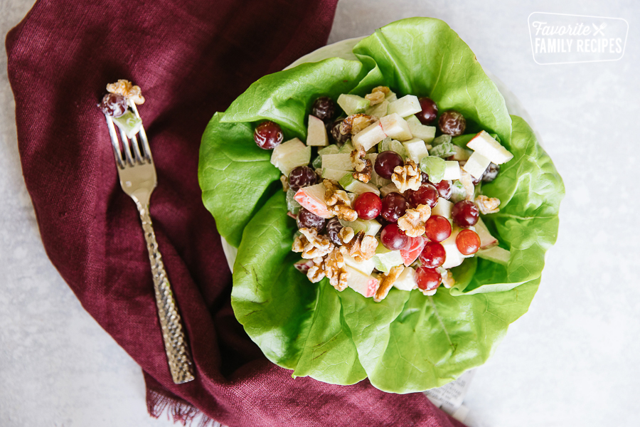 A Waldorf salad on a leaf of butter lettuce with a fork to the side.