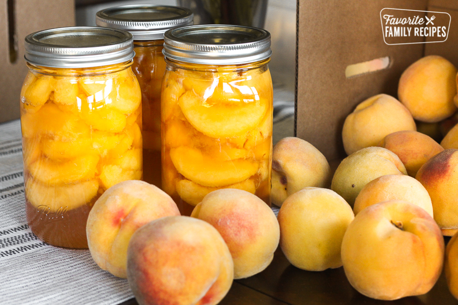 Canning peaches at home. Bottles of home canned peaches surrounded by fresh peaches