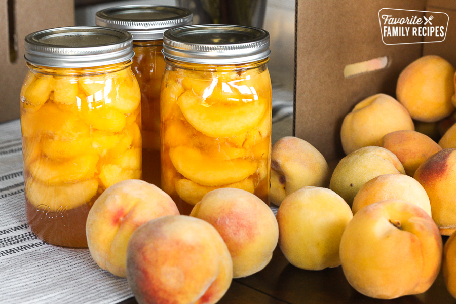 Canning peaches at home. Bottles of home canned peaches surrounded by fresh peaches.