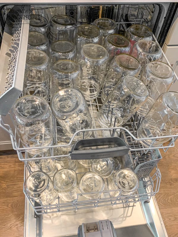 Glass jars in the dishwasher to be sterilized for canning peaches.