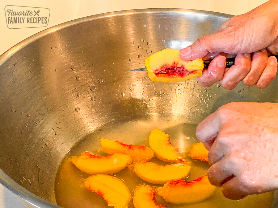 Fresh peaches being sliced into a large bowl