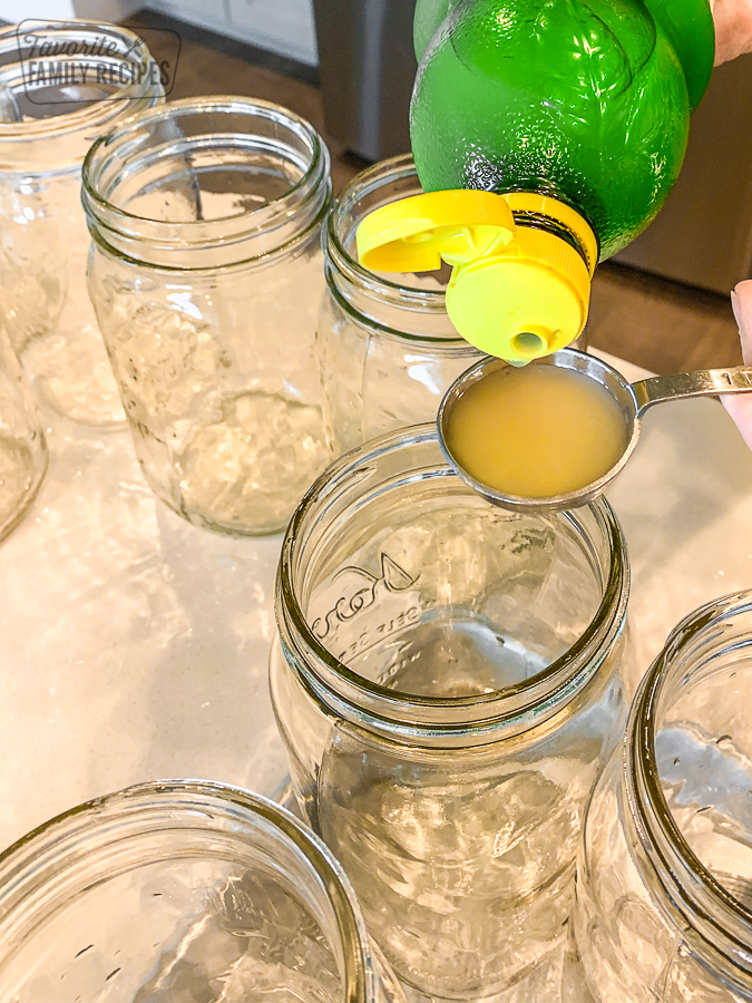 Lemon juice is being added to glass jars prepared for canning
