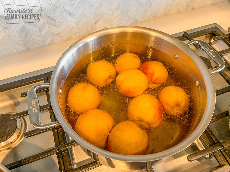 Peaches being boiled in a large pot on the stove