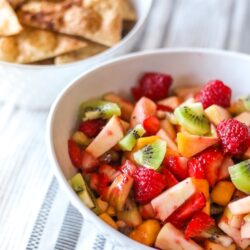Fruit salsa in a white bowl in front of cinnamon chips in a white bowl.