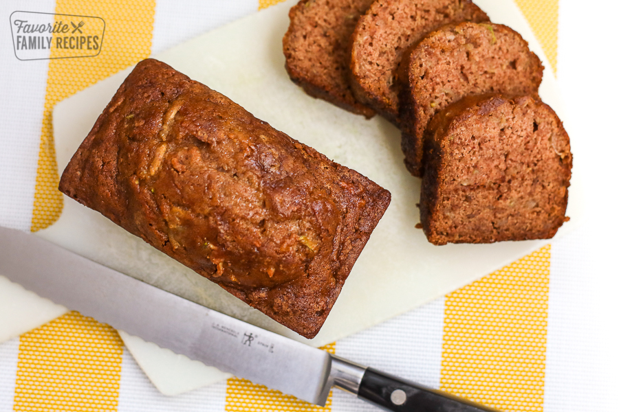 A loaf of gluten free zucchini bread on a cutting board with slices on the side.