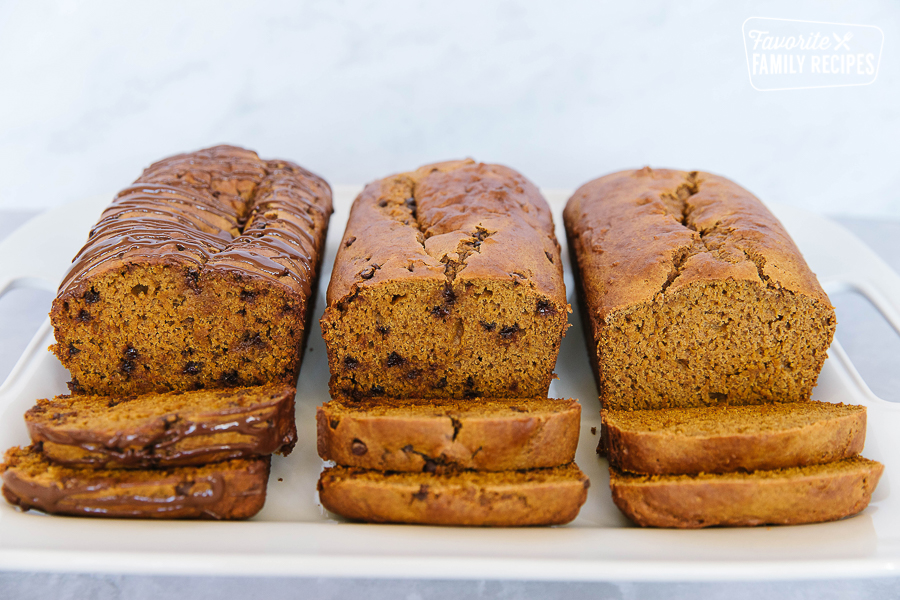 3 loaves of pumpkin bread with two cut slices off of each loaf. 