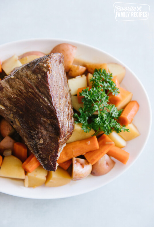 White plate with Crockpot Roast Beef and carrots and potatoes on it