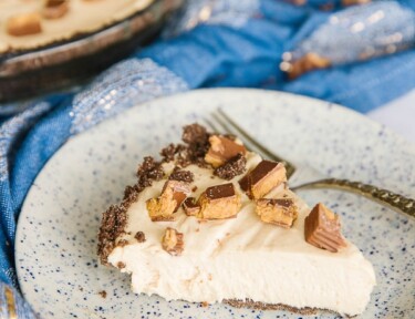 Side view of a slice of Creamy Peanut Butter Pie with a whole pie in the background