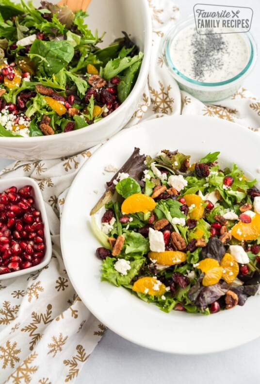 Christmas Salad in a white bowl with a bowl of pomegranate seeds