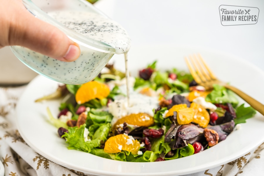 Poppyseed dressing being poured over a salad