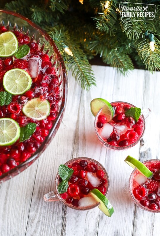 Three punch glass filled with holiday punch and a lime wedge on the side