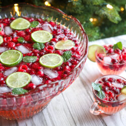 Holiday punch in a punch bowl with three clear glass cups of punch to the side
