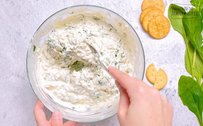 Mixing spinach dip ingredients together in a large bowl