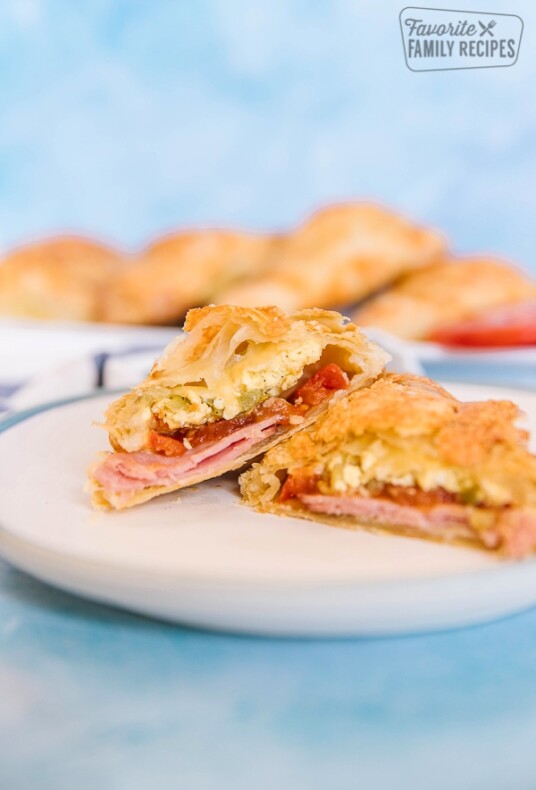 A ham and egg breakfast hand pie on a white plate with a blue background