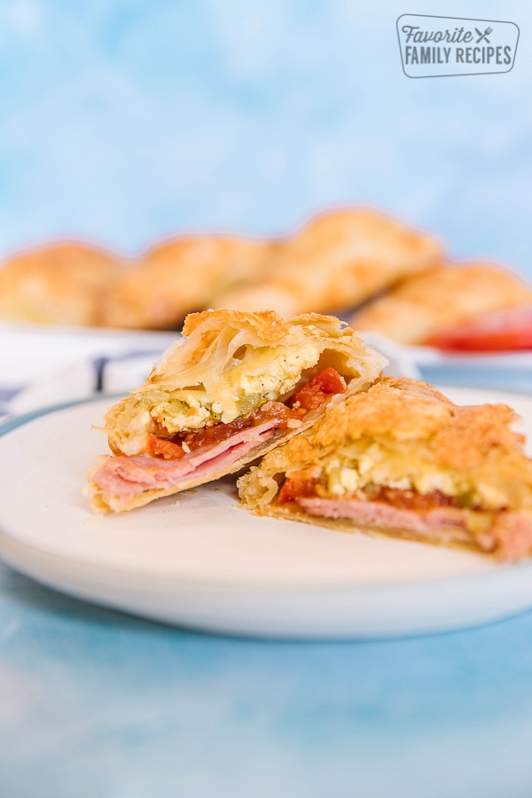 A ham and egg breakfast hand pie on a white plate with a blue background