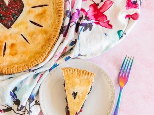 A full berry pie and a sliced piece of berry pie