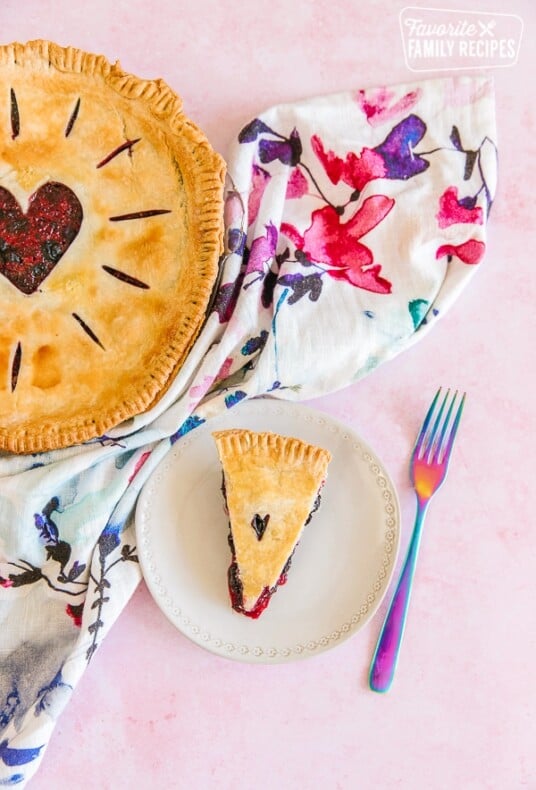 A full berry pie and a sliced piece of berry pie