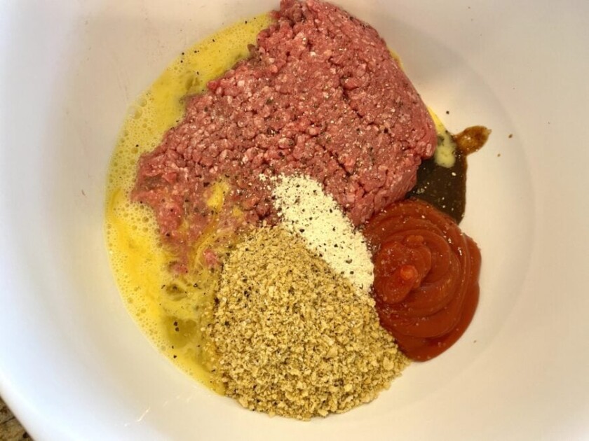 Meatloaf ingredients including bread crumbs, egg, ketchup, and salt in a bowl