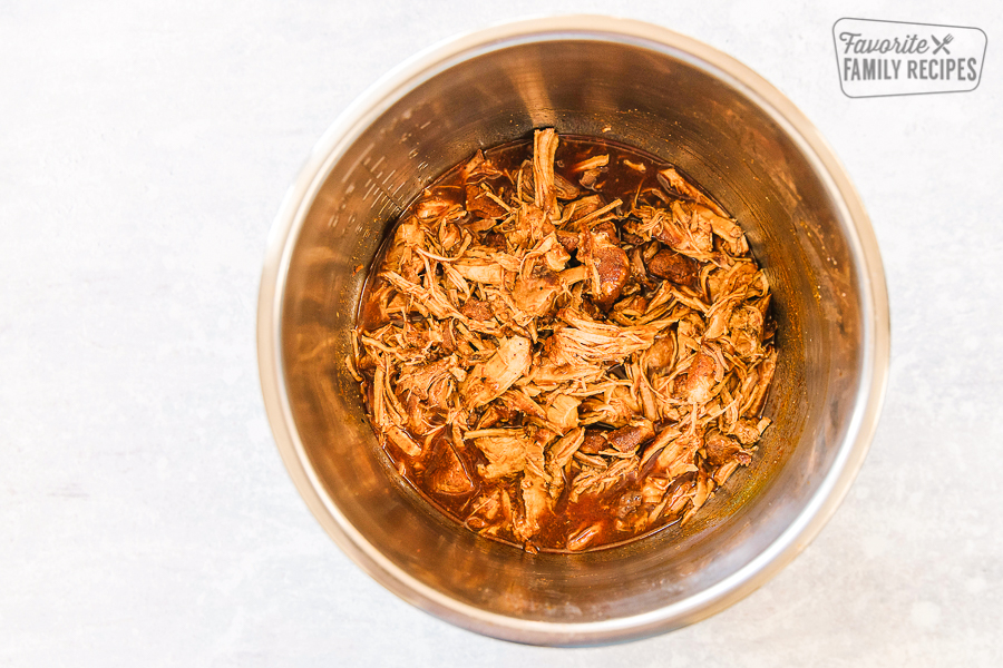 An instant pot full of bbq pulled pork on a white background.