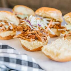 Six instant pot pulled pork sandwiches on a white plate.