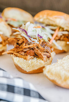 Six instant pot pulled pork sandwiches on a white plate.