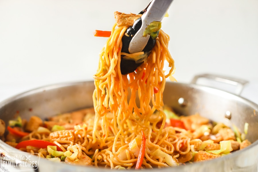 Yakisoba in a skillet being served with tongs.