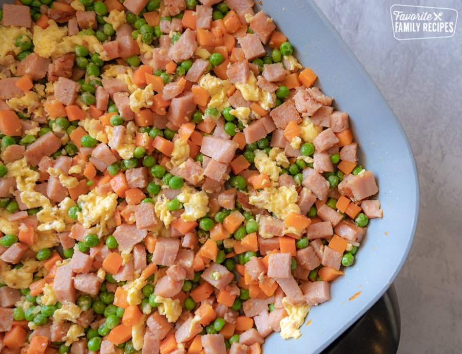 A skillet full of peas, corn, eggs, carrots, and ham.
