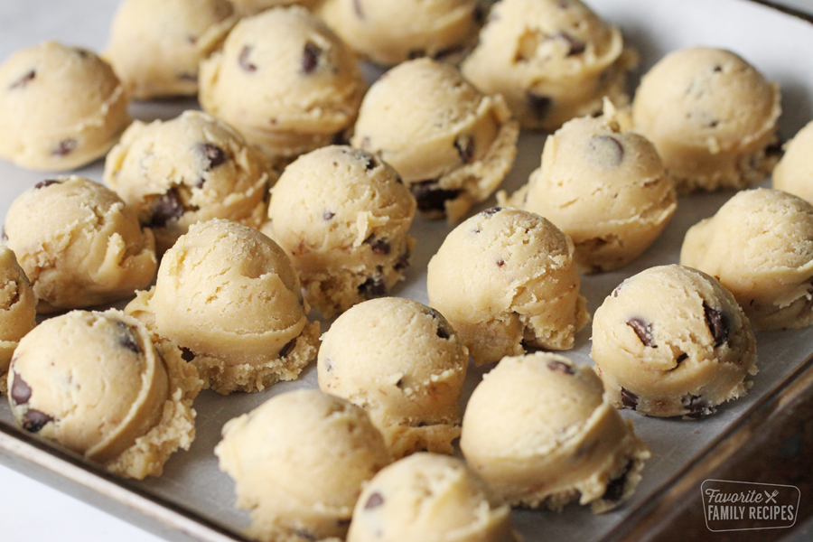 How to freeze cookie dough using the "scoop" method so you can have a warm, chewy treat any time that cookie craving hits! It is a quick and easy recipe to have cookies year-round! Cookie dough scoops on a baking sheet.