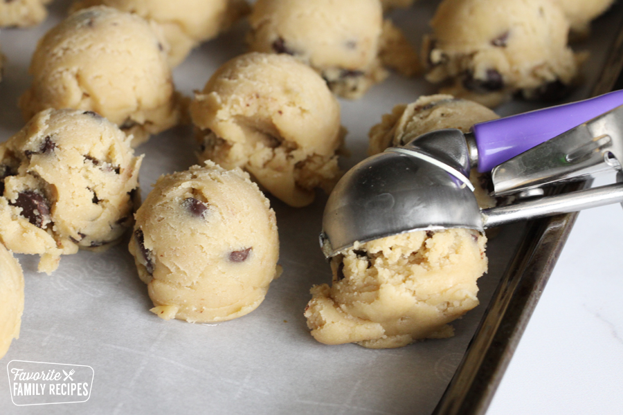 Cookie dough being scooped on a baking sheet.