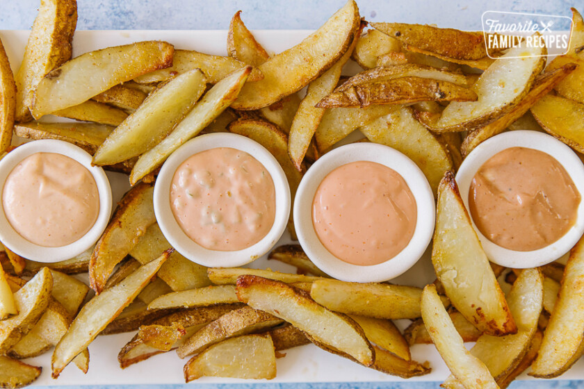 4 varieties of fry sauce on a white tray surrounded by French fries