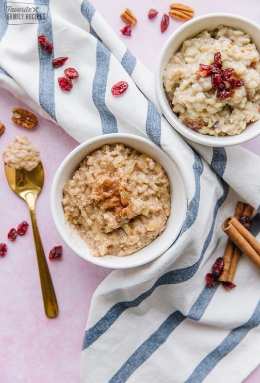 Two bowls of oatmeal on a striped tea towel.