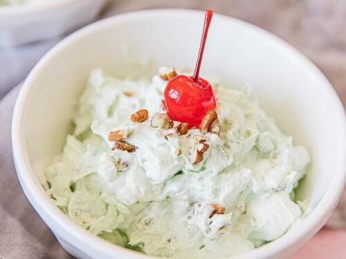 Watergate Salad in a white bowl with a cherry on top