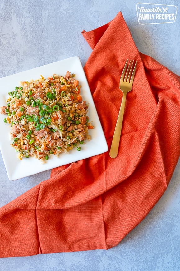A square plate of Cauliflower Fried Rice with a napkin and fork