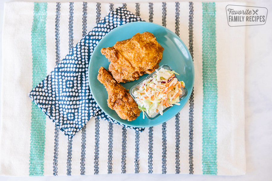 KFC Coleslaw with fried chicken on the side served on a striped blue placemat