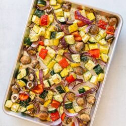 Oven roasted vegetables sprinkled with rosemary on a baking pan