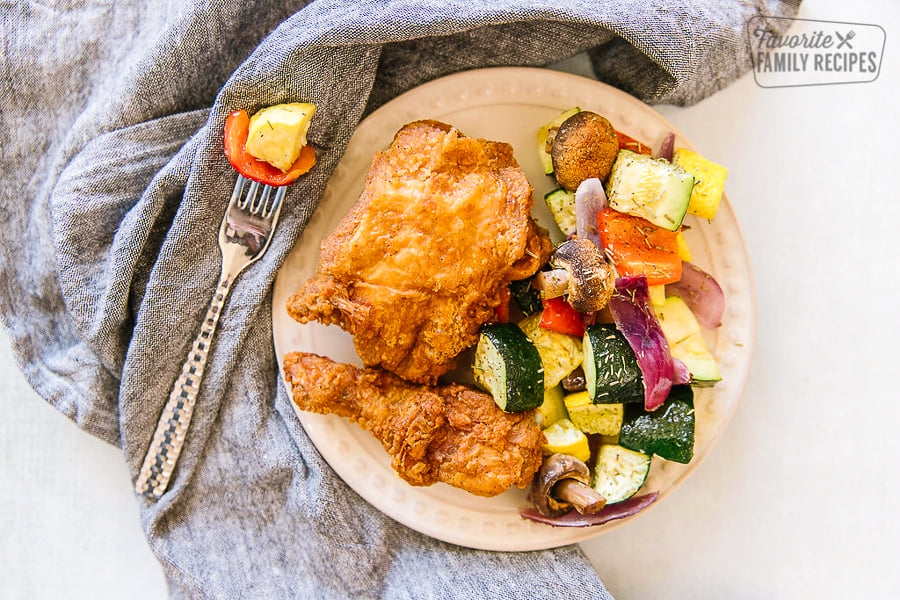 Fried chicken and oven roasted vegetables on a serving plate.