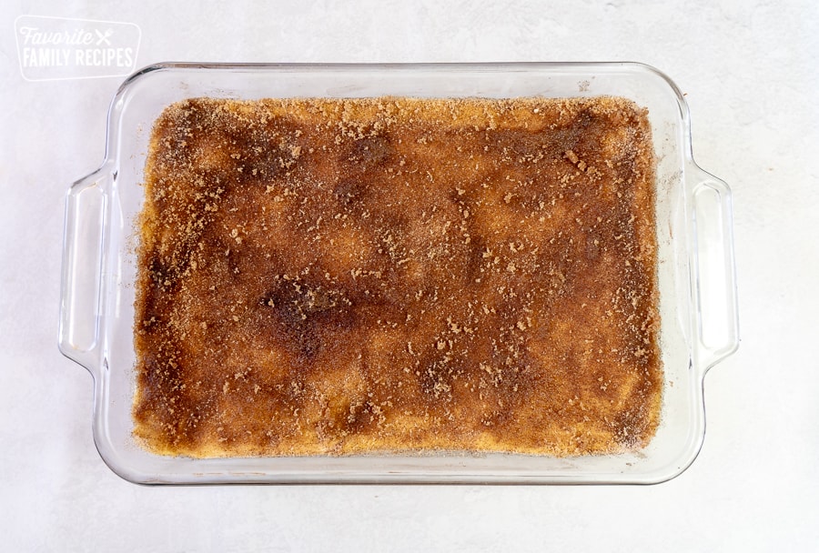 Cinnamon sugar sprinkled over the top of sopapilla cheesecake bars in a 9x13 pan