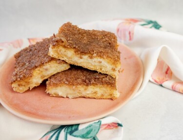 A stack of sopapilla cheesecake bars on a pink plate