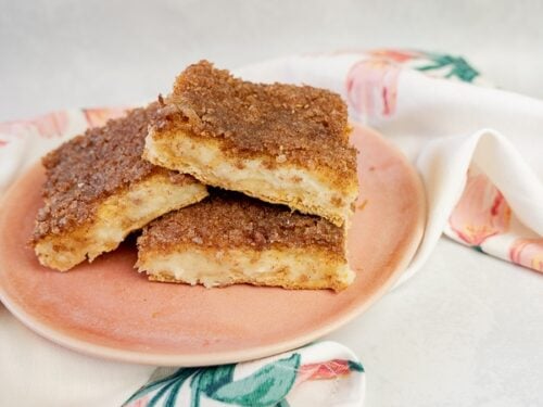 A stack of sopapilla cheesecake bars on a pink plate