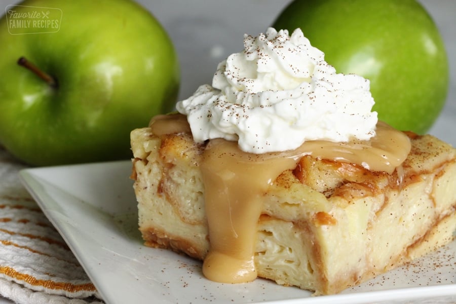 A slice of bread pudding on a plate topped with caramel sauce and whipped cream.