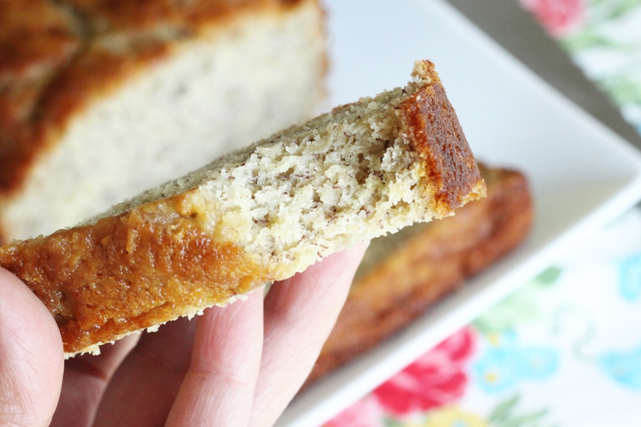 A handheld slice of banana bread with a bite taken out of it.