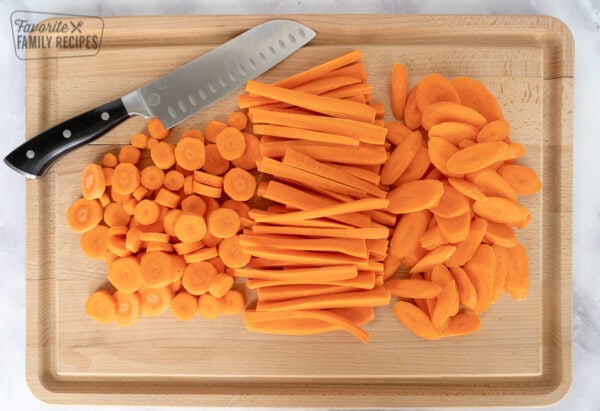 Sliced carrots on a cutting board with a knife.
