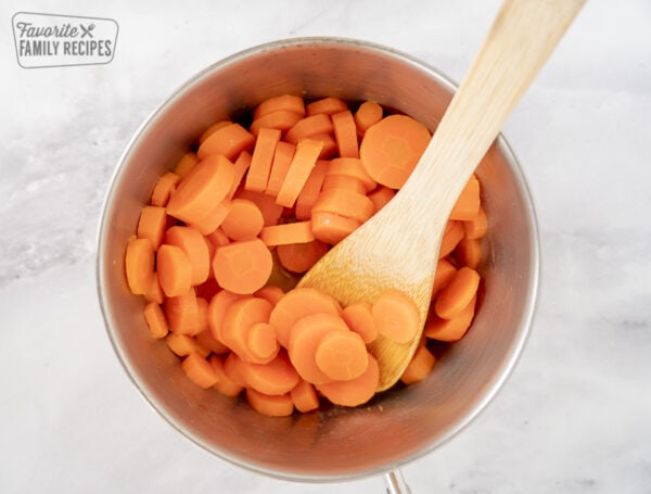 Sliced carrots in a pan with wooden spoon