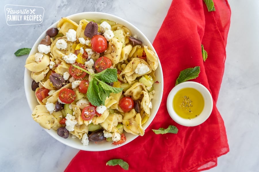 Tortellini salad with a little bowl of olive oil and a red napkin.